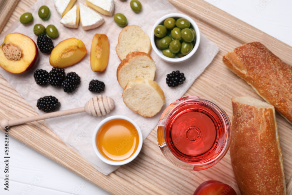 Glass of delicious rose wine and snacks on white wooden table, top view Glass of delicious rose wine and snacks on white wooden table, top view