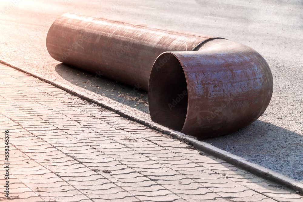 a new fitting pipe turn lies on the pavement waiting for the repair of the main pipe a new fitting pipe turn lies on the pavement waiting for the repair of the main pipe