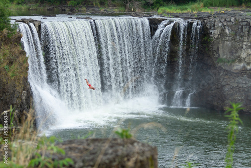 A men is diving from a cliff at Jingbo Lake falls in Heilongjiang, China. Waterfall and Mountain landscape.