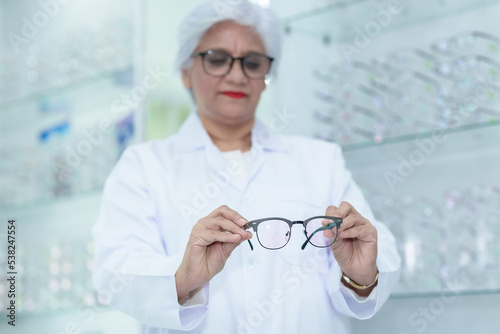  Middle aged ophthalmologist holding eyeglasses and examining them  focus on eyeglasses  close-up