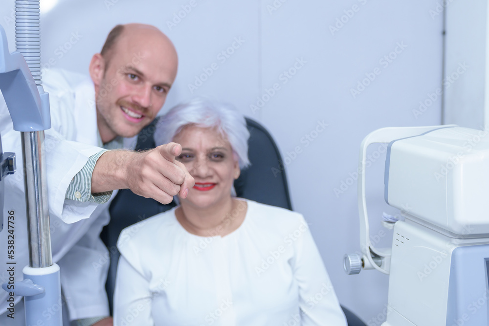 Attractive male ophthalmologist is checking eye vision of middle aged woman in modern clinic, doctors and ophthalmology clinic patients. Attractive male ophthalmologist is checking eye vision of middle aged woman in modern clinic, doctors and ophthalmology clinic patients.