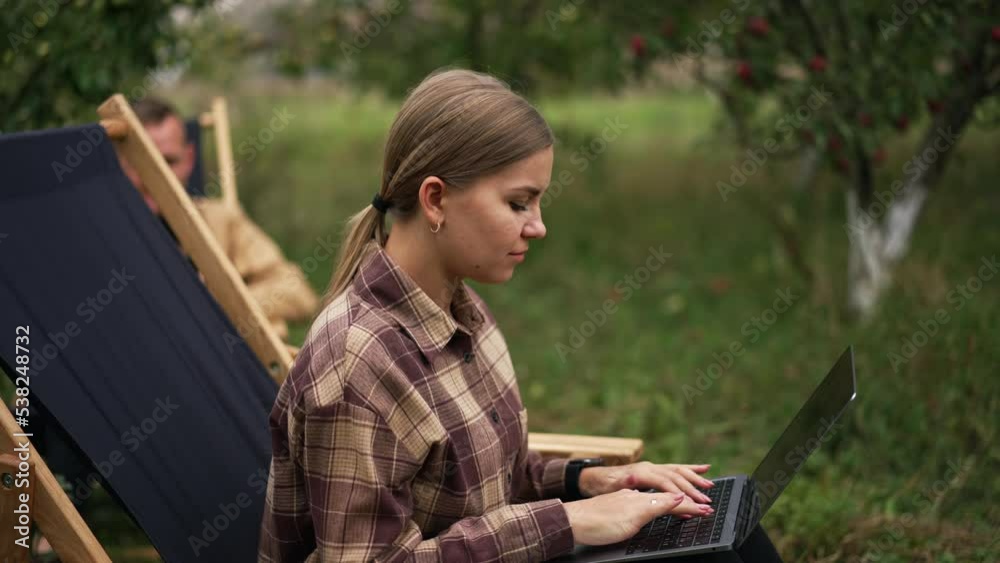 Married couple both working remotely in their garden. People feeling happy having freelance work in the comfortable place. Nature backdrop. Married couple both working remotely in their garden. People feeling happy having freelance work in the comfortable place. Nature backdrop.