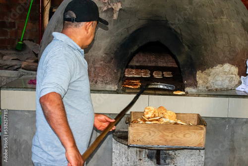 Baker cooking bread the traditional way, in a dome-shaped wood-fired oven, in Chilca - Peru