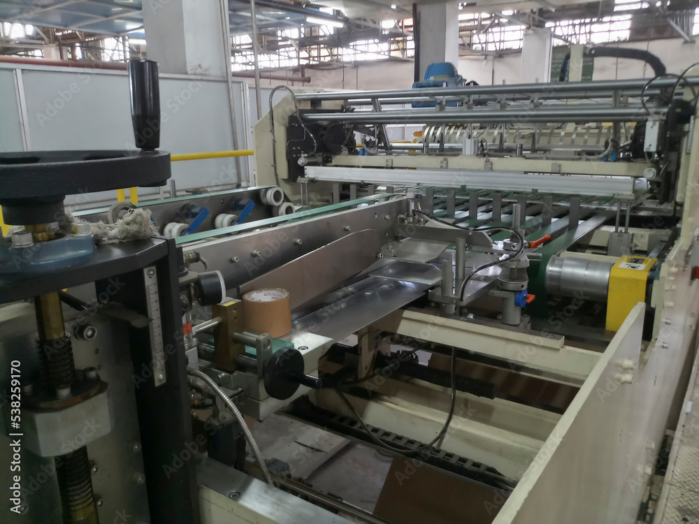 Kolkata, West Bengal, India - 16th May 2019 : Manufactured white Paper sheets are being slitted and rewinded in paper slitting and rewinding machine. in a paper manufacturing plant. Kolkata, West Bengal, India - 16th May 2019 : Manufactured white Paper sheets are being slitted and rewinded in paper slitting and rewinding machine. in a paper manufacturing plant.
