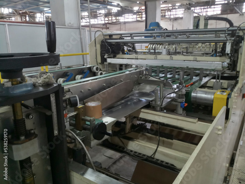 Kolkata, West Bengal, India - 16th May 2019 : Manufactured white Paper sheets are being slitted and rewinded in paper slitting and rewinding machine. in a paper manufacturing plant.