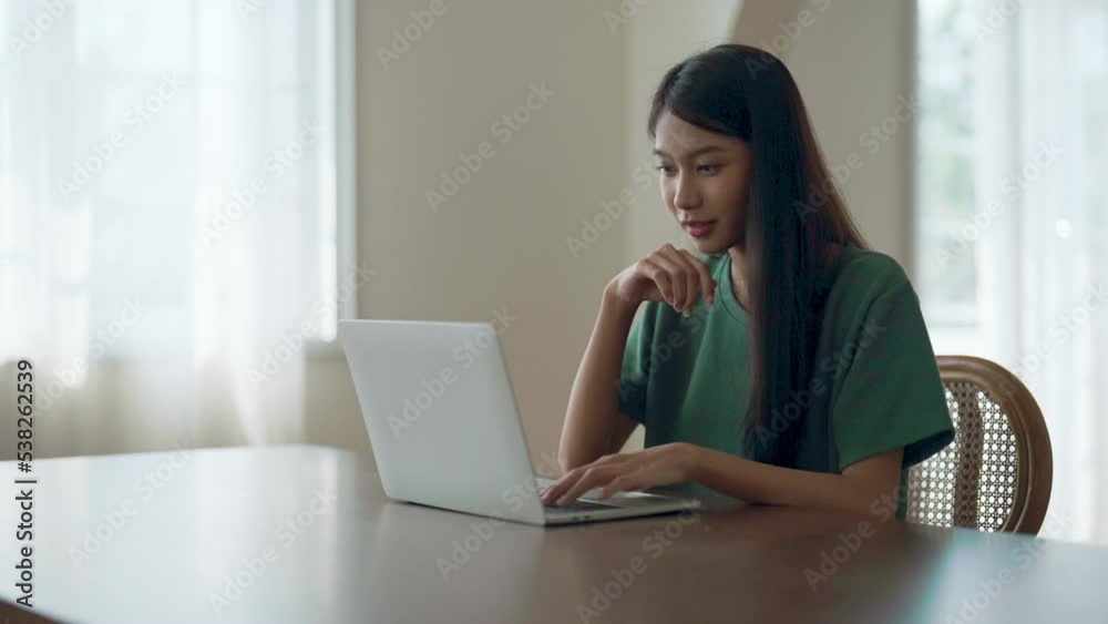 Young asian woman working at home. Female using computer laptop on desk at house