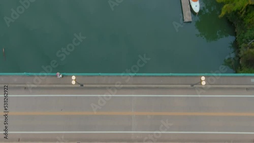  aerial footage of the Henley Street Bridge and Gay Street Bridge over the Tennessee River at sunset surrounded by autumn colored trees, lush green trees and cars driving on the street in Knoxville photo