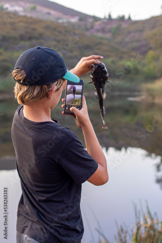 Photography Teenager taking photo of the fish he caught