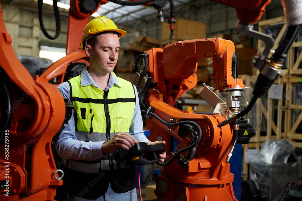 factory worker or engineer operating remote switch controller to control robot machine in the factory factory worker or engineer operating remote switch controller to control robot machine in the factory