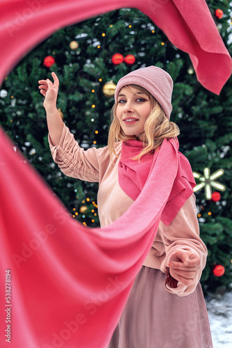New Year's photos of a beautiful girl in the forest with a decorated Christmas tree, filled with comfort and magic. Magic. A girl and a scarf flying around the frame, twisted