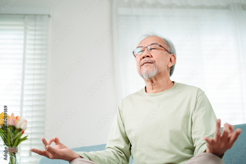 Asian elderly senior old man doing yoga relax in living room at home, Mature retirement happy healthy lifestyle concept..