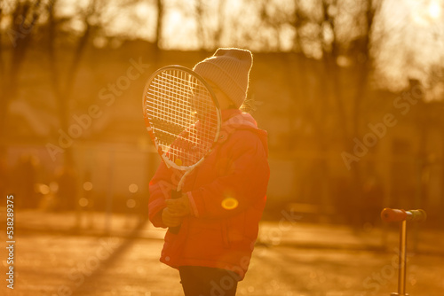 Portrait of a cute little girl playing tennis.