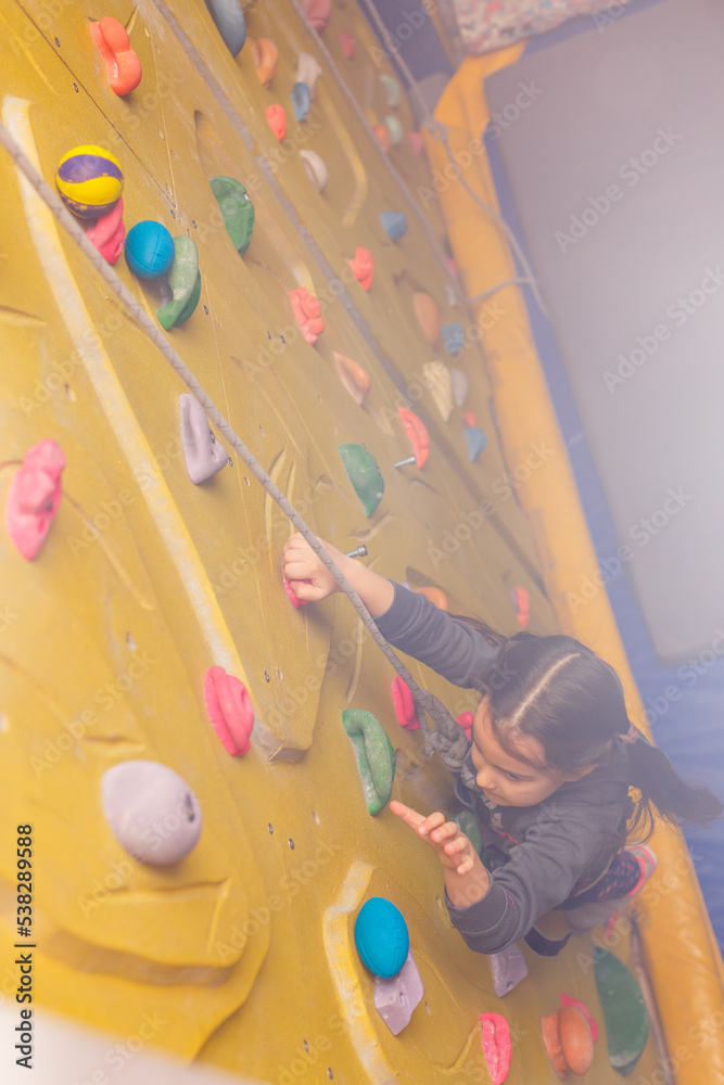 Little girl ascending in outdoor rock climbing gym