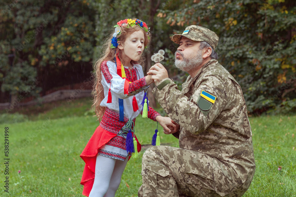 Portrait of a Ukrainian little girl with her military father in the park.