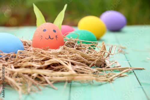 straw basket with easter eggs on wooden background