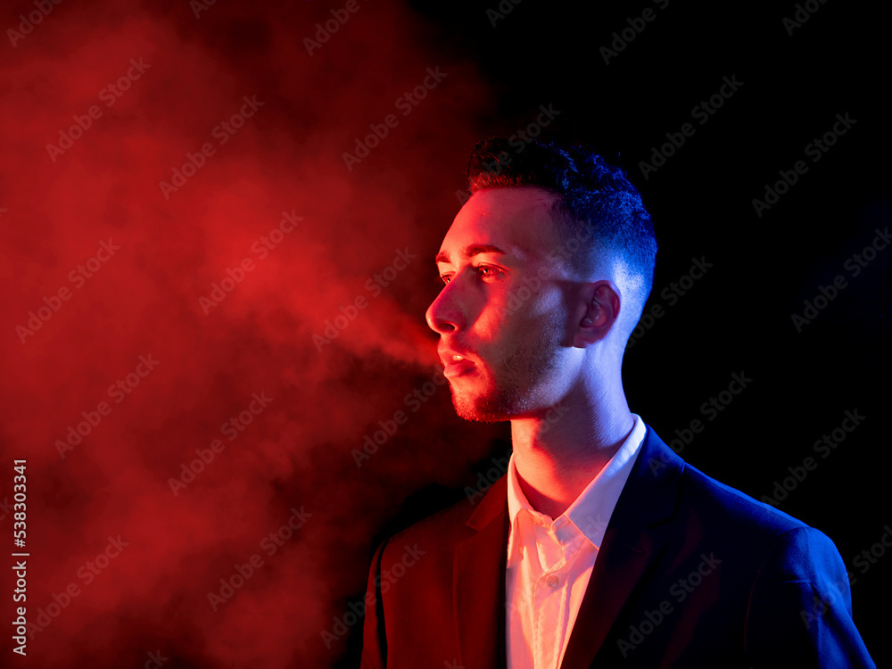 Elegant young man blowing cigarette smoke out of his mouth on a black background. Selective focus Elegant young man blowing cigarette smoke out of his mouth on a black background. Selective focus