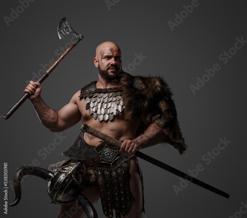 Portrait of strong viking warrior from past with two axes dressed in fur and armour.