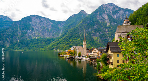 Famous view of Hallstatt city and church near the lake. Mountains in the background. Summer rainy day, soft colors, cloudy weather. © Martin