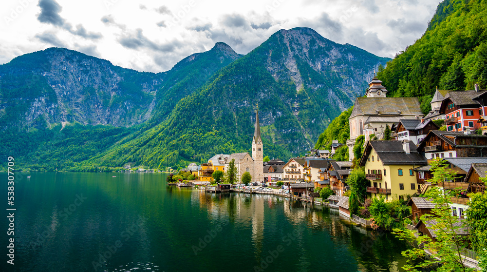 Famous view of Hallstatt city and church near the lake. Mountains in the background. Summer rainy day, soft colors, cloudy weather.