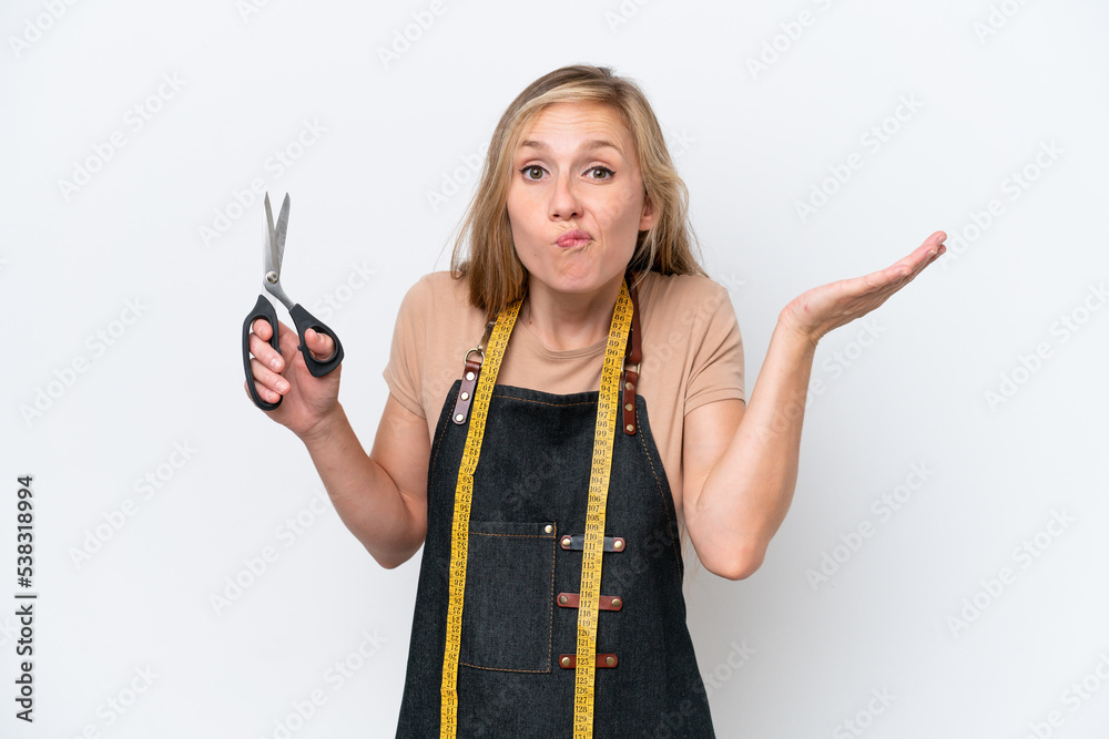 Young blonde seamstress woman isolated on white background having doubts while raising hands Young blonde seamstress woman isolated on white background having doubts while raising hands