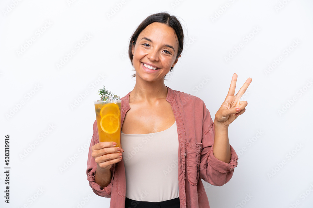 Young hispanic woman holding a cocktail isolated on white background smiling and showing victory sign Young hispanic woman holding a cocktail isolated on white background smiling and showing victory sign