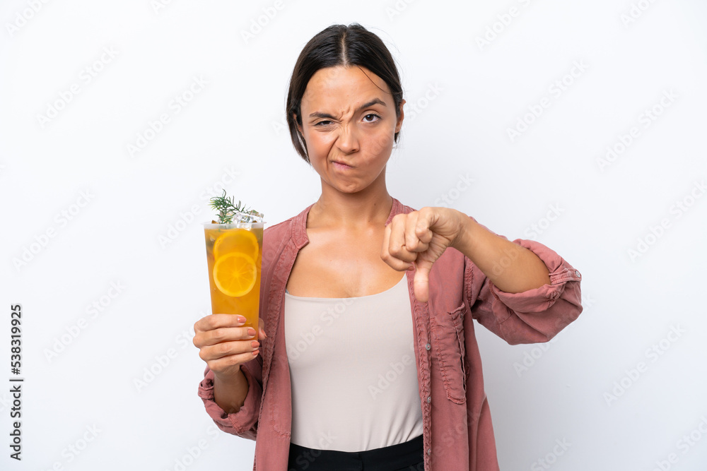 Young hispanic woman holding a cocktail isolated on white background showing thumb down with negative expression Young hispanic woman holding a cocktail isolated on white background showing thumb down with negative expression