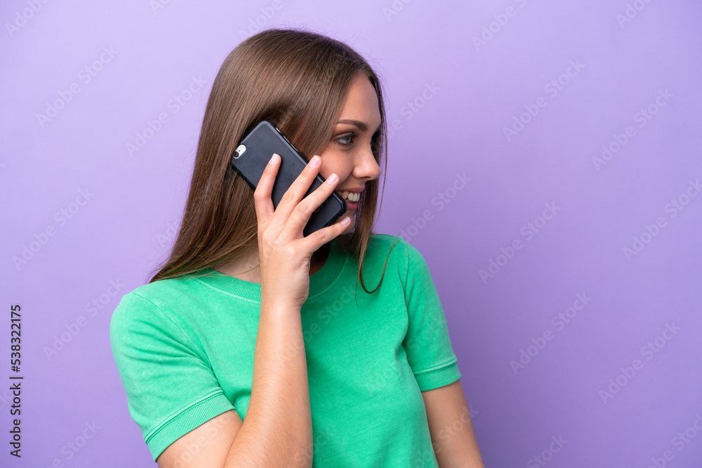 Young caucasian woman isolated on purple background keeping a conversation with the mobile phone with someone Young caucasian woman isolated on purple background keeping a conversation with the mobile phone with someone