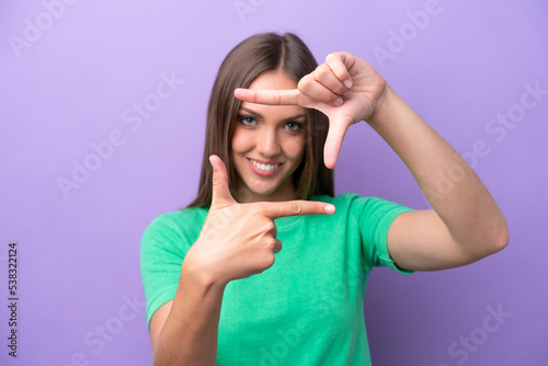 Young caucasian woman isolated on purple background focusing face. Framing symbol