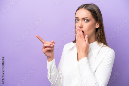 Young caucasian woman isolated on purple background with surprise expression while pointing side
