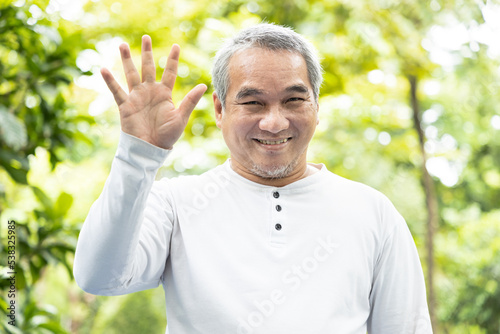 Confident happy smiling old asian man pointing up 5 fingers photo