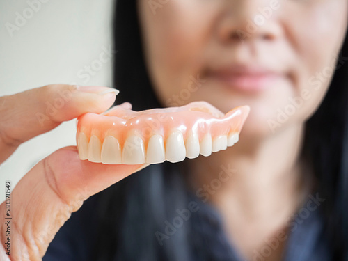 Happy asian woman  be smile and holding dentures in hand. photo