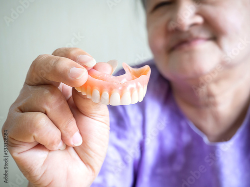 Asian Elderly woman be smile and holding dentures in hand.