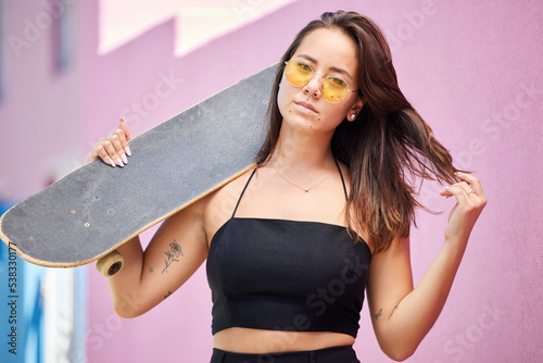 Portrait of woman, sunglasses and skateboard retro look in urban city on street style adventure. Young asian trendy skater girl, gen z or millennial lifestyle and fun modern edgy fashion outdoors photo