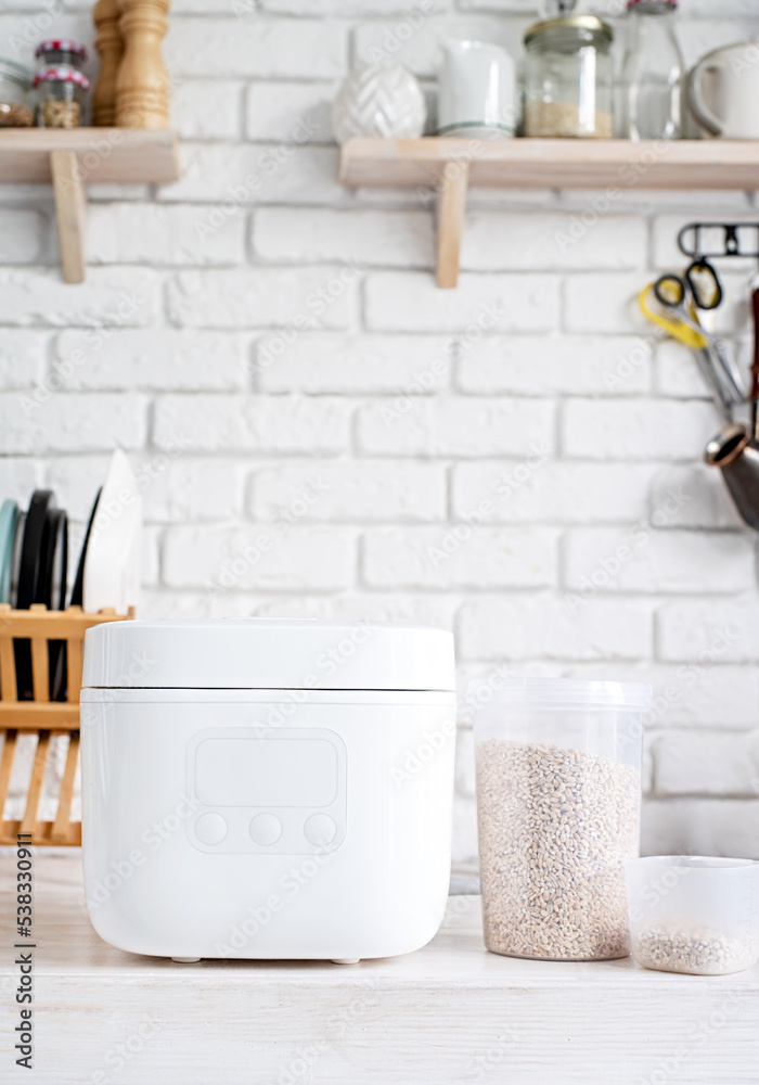 Electric rice cooker on wooden counter-top in the kitchen Electric rice cooker on wooden counter-top in the kitchen
