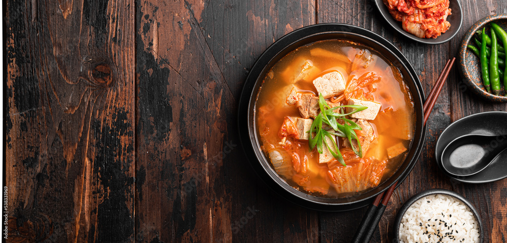 Korean food, kimchi soup with tofu in a ceramic bowl on a wooden background, top view, copy space Korean food, kimchi soup with tofu in a ceramic bowl on a wooden background, top view, copy space