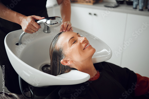 Woman, salon and hair care in wash treatment for beauty, luxury and relax with smile indoors. Happy female enjoying calm relaxation smiling in happiness for clean, service and style by hairdresser