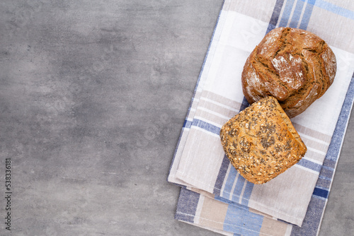 Gold rustic crusty loaves of bread and buns on wooden background. Still life captured from above top view, flat lay.