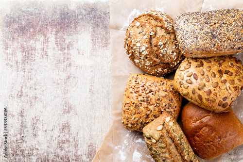 Gold rustic crusty loaves of bread and buns on wooden background. Still life captured from above top view, flat lay.