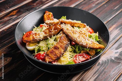 Caesar Salad with Salmon on wooden table