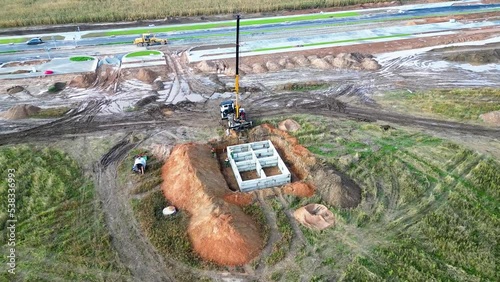 Crane assembles foundation blocks at the construction site. View from above. Drone photography. Prefabricated foundation of reinforced concrete blocks.