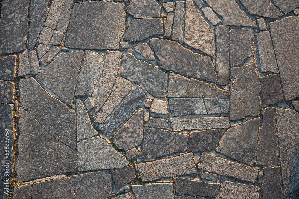 Obraz premium The surface of the pavement laid with granite slabs. Stone surface illuminated by sunlight