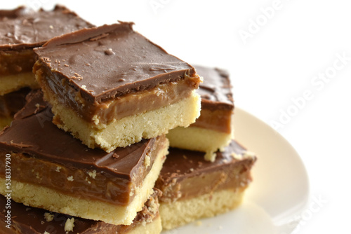 Millionaire's shortbread with chocolate and caramel on a parchment paper with copy space on the right side.	
