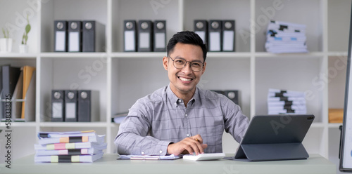 Young handsome asian Ceo manager businessman middle-aged man around the age of 35 sitting in office near windows holding hands looking at camera and smile. photo