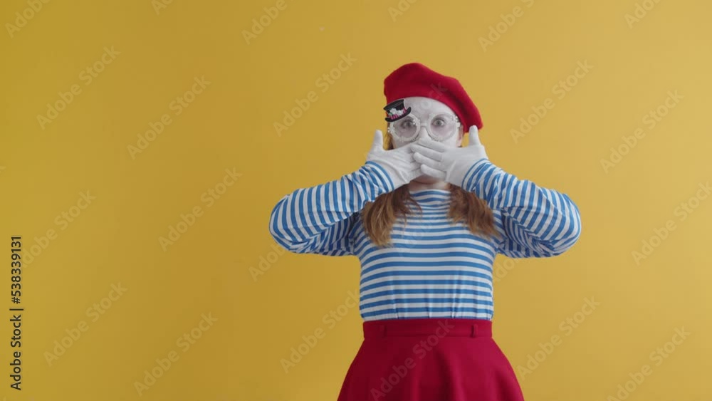 Mime woman is surprised by looking into camera with her mouth open, covering it with her hands, concept of surprise. Shocked mime woman in a striped T-shirt and beret, spreads hands in surprise