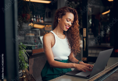 Laptop, internet cafe and typing with a black woman blogger working at the window of a coffee shop on an article or report. Computer, email and remote work with a female writer busy in a restaurant