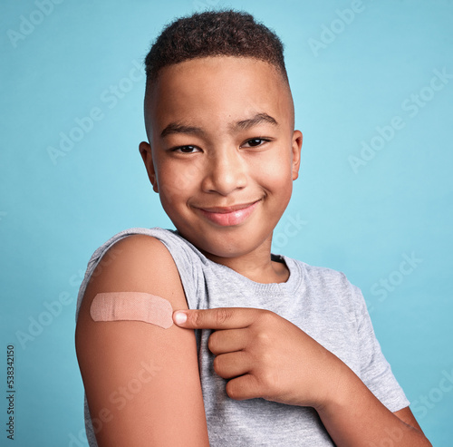 Valokuva .Child black, band aid and happy kid with vaccine, in blue studio background and
