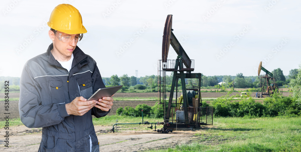 © scharfsinn86 - Engineer with a digital tablet on the background of oil rigs