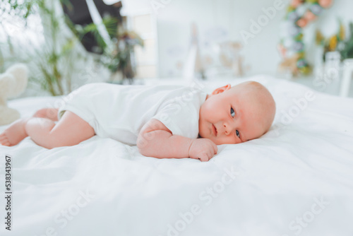 Cute 2-month-old baby lying on the bed, natural bed linen. delicate baby skin.
