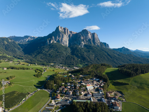Dolomites alp Seiser Alm beautifull majestic mountain in Tirol north of Italy aerial drone overview. Small village and alp houses in grass field landscape. Nature cottage adventure.
