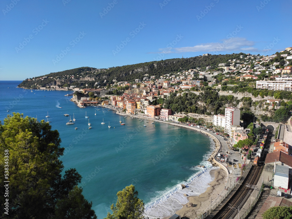 View of Port Villefranche-Santé with boats, catamarans, sails boats, speed boats, and yachts moored to the pier, during daytime with a clear blue sky, Villefranche-sur-Mer, France.